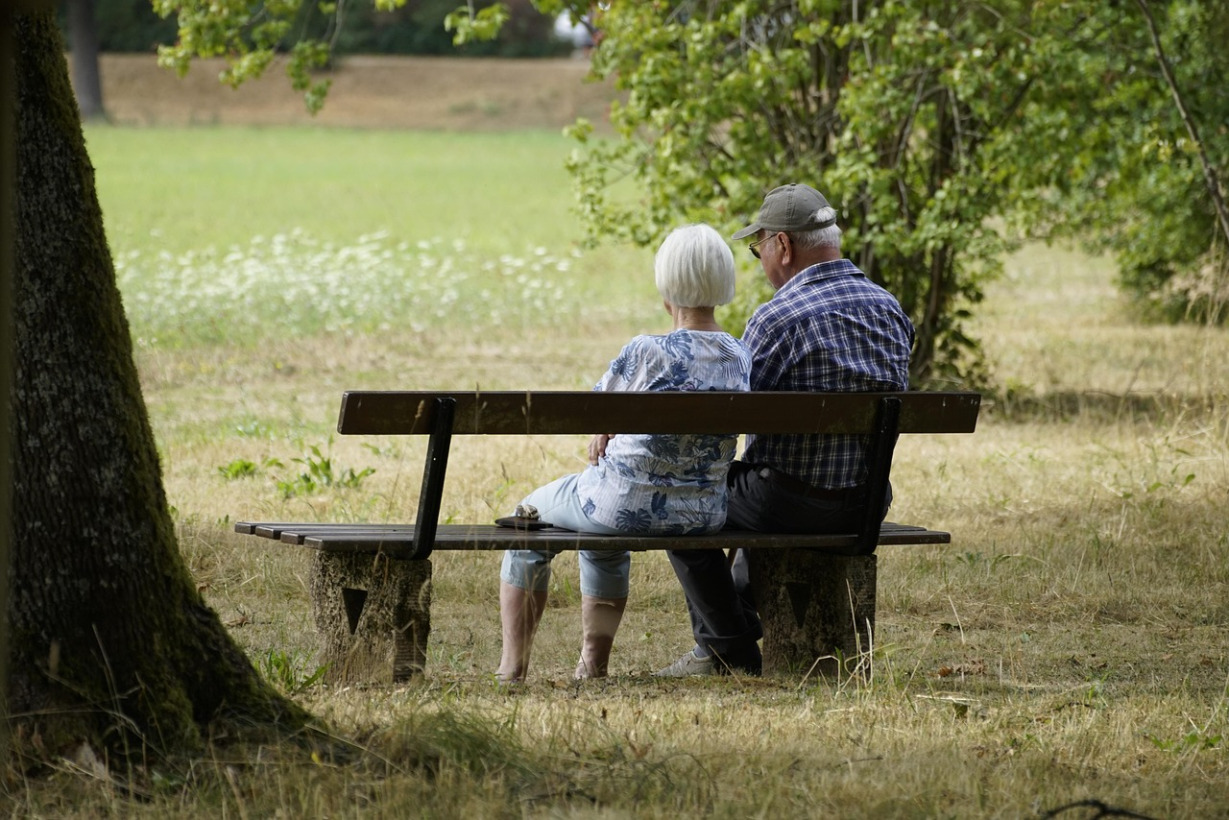 An older couple sitting together on a park bench